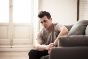 Man sitting on couch and thinking about his kratom drug misuse