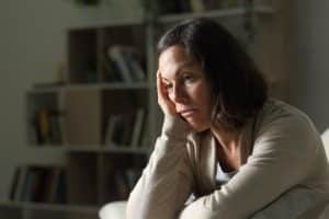 a woman sits on a couch with one hand on her head