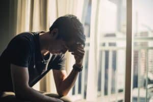 a man holds his head and looks down at the floor