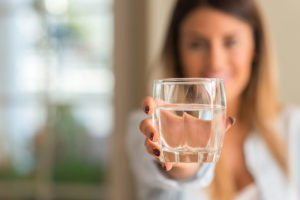 a person holds a gladd of water find out how Water helps liver