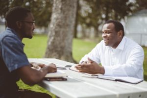 two people sit at a bench possibly discussing What is a serenity prayer