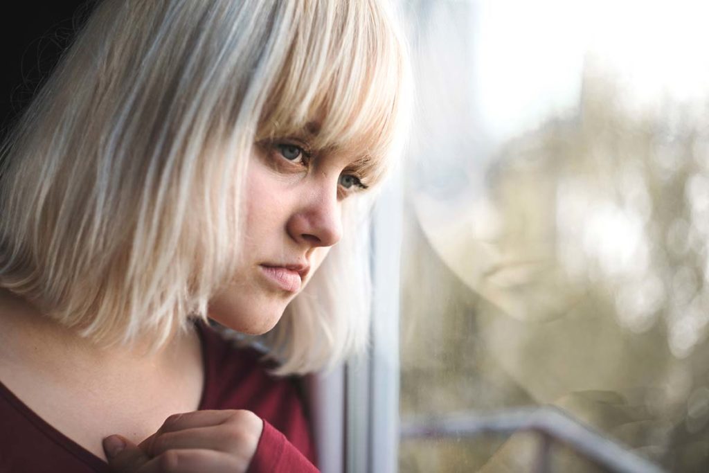 a person stares out of a window possibly wondering about the causes of schizophrenia