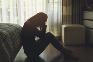 Person sitting on floor while thinking of the signs that it's time for opioid rehab